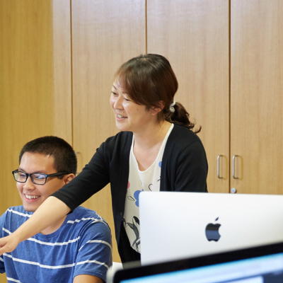 Sharla Hanaoka helping a student on a computer.