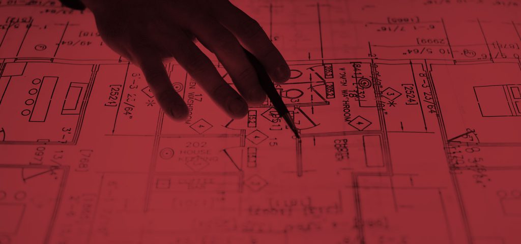 Closeup of a hand with a pencil on top of a blueprint.