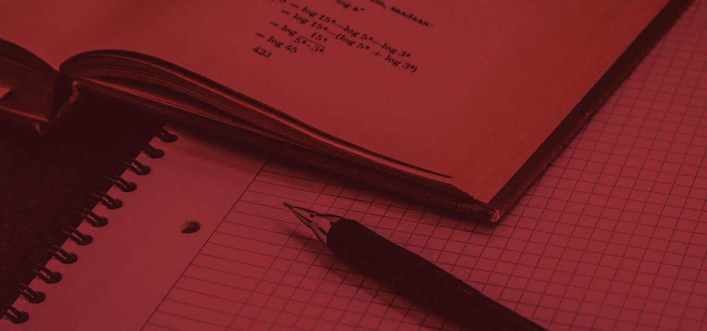 Close-up of a textbook and pen laying on graph paper.