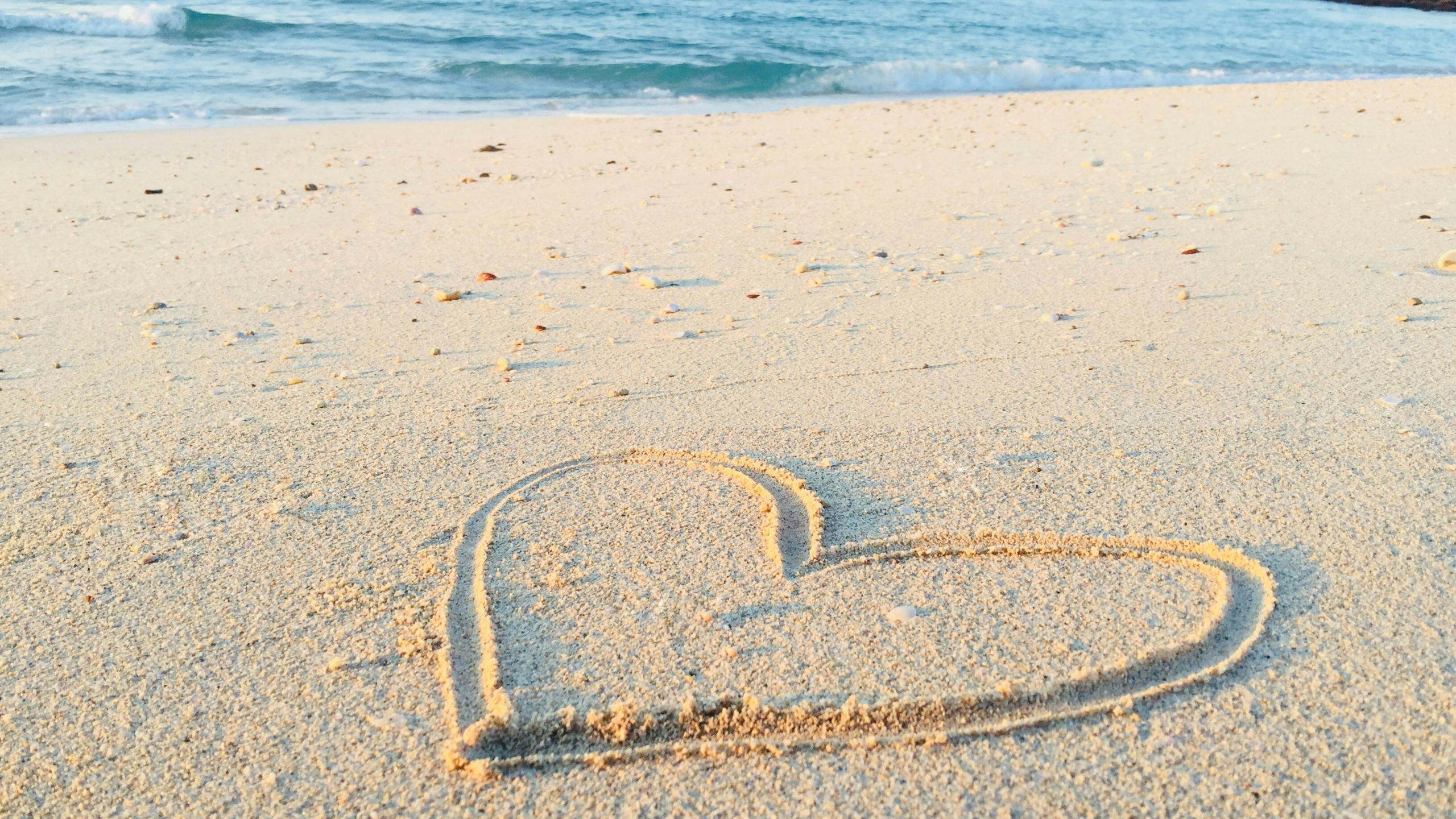 A heart is drawn in beach sand.