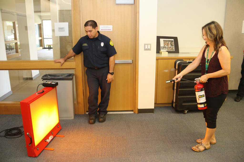 UHWO Human Resources Specialist Nancy Nakasone extinguishing a simulated flame during fire safety training.