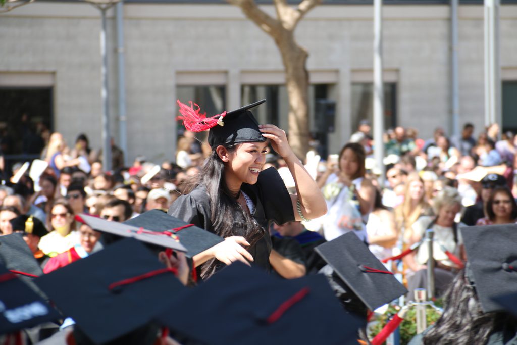 A happy UH West Oʻahu graduate smiles as she walks to receive her diploma from Interim Chancellor Doris Ching at the spring 2016 commencement. 