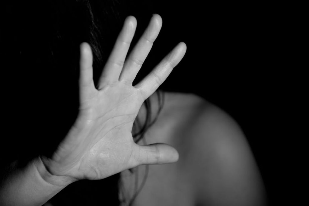 Dark photo of woman with hand up, shielding herself
