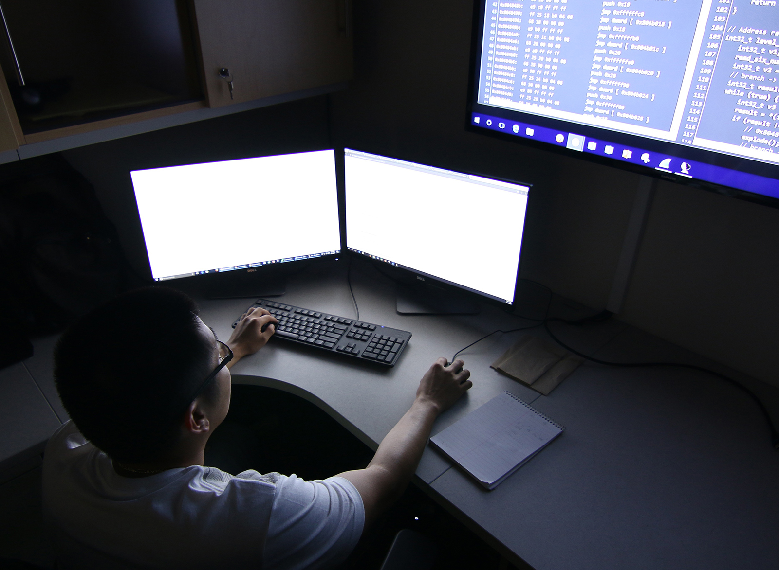 A UH West Oʻahu cyber security student sits in front of monitors.