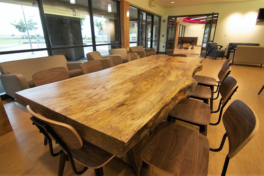 Photo of a long table and room at the Nāulu Center, which includes a lounge area where students can relax or work in groups. The center's multipurpose room can been seen in the background.