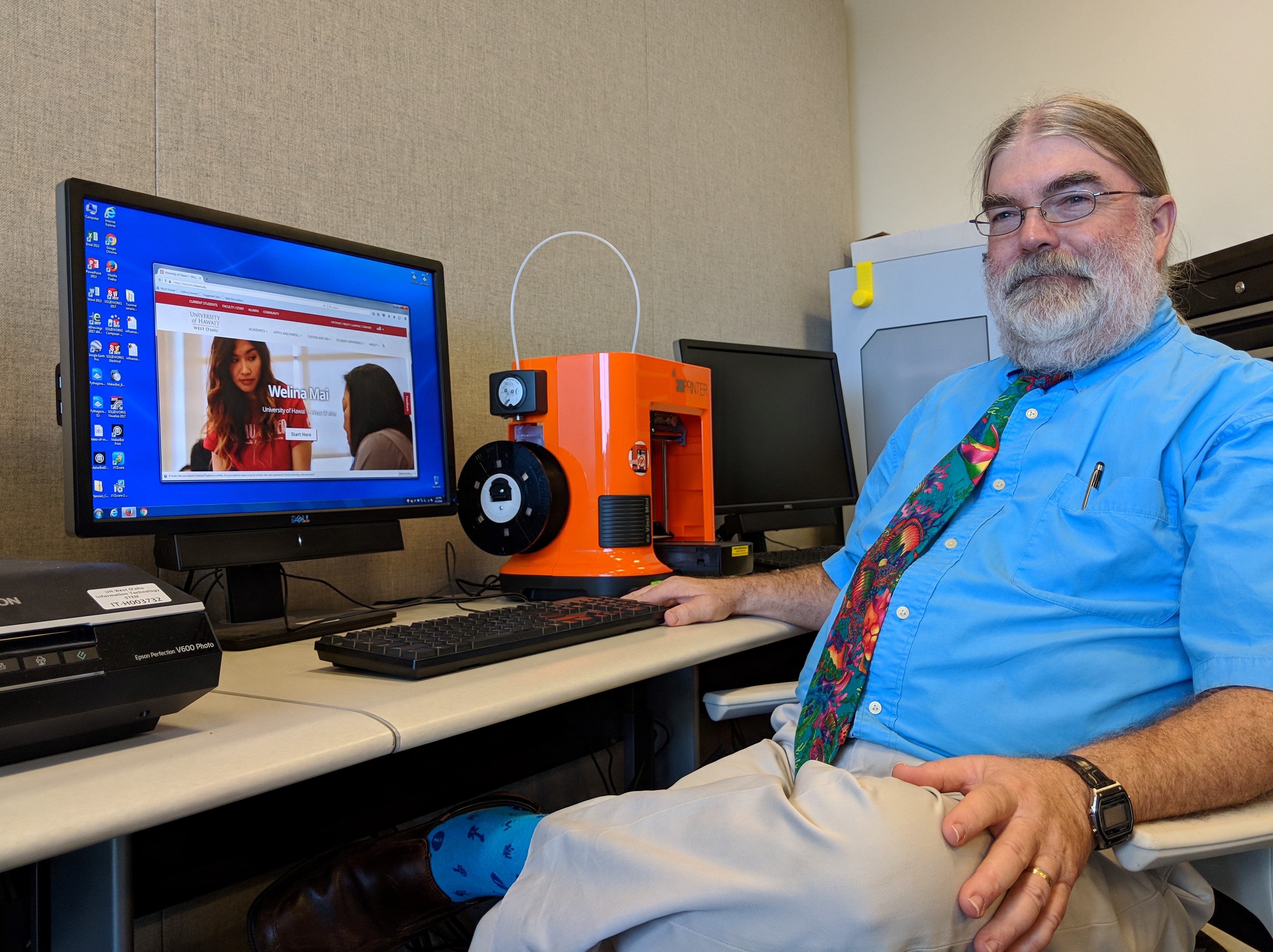Photo of Dr. Richard Jones in front of a computer and 3-D printer in the Pueo Prototyping Lab
