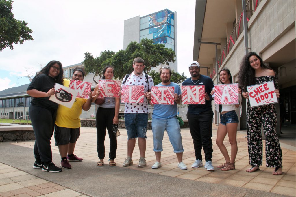 eight students holding signs spelling out Welina and saying Chee Hoot