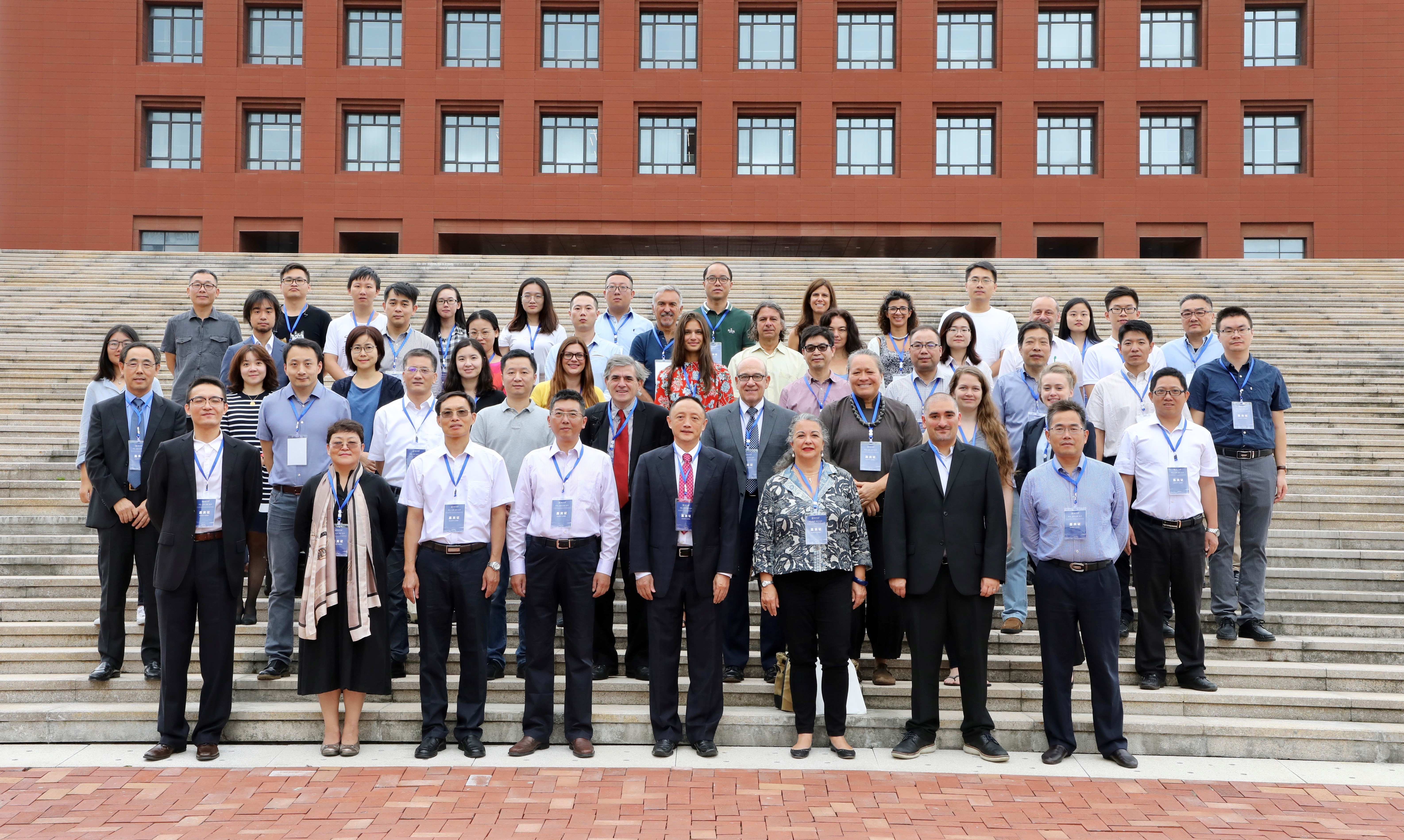Photo of conference participants standing for an official photo on stairs in front of a brick building