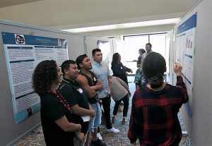 Photo of people looking at a research poster with one person pointing to it