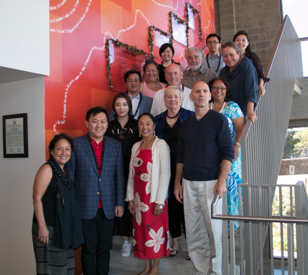 Photo of 14 people standing on stairs in front of an orange wall