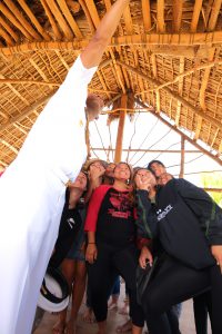 Man in a white uniform stretching his arm up high to take a selfie with students