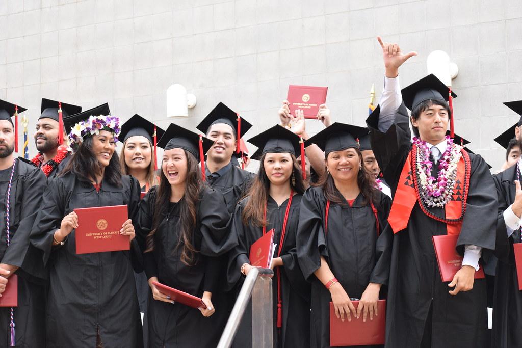 photo of graduates standing and celebrating during a commencement ceremony
