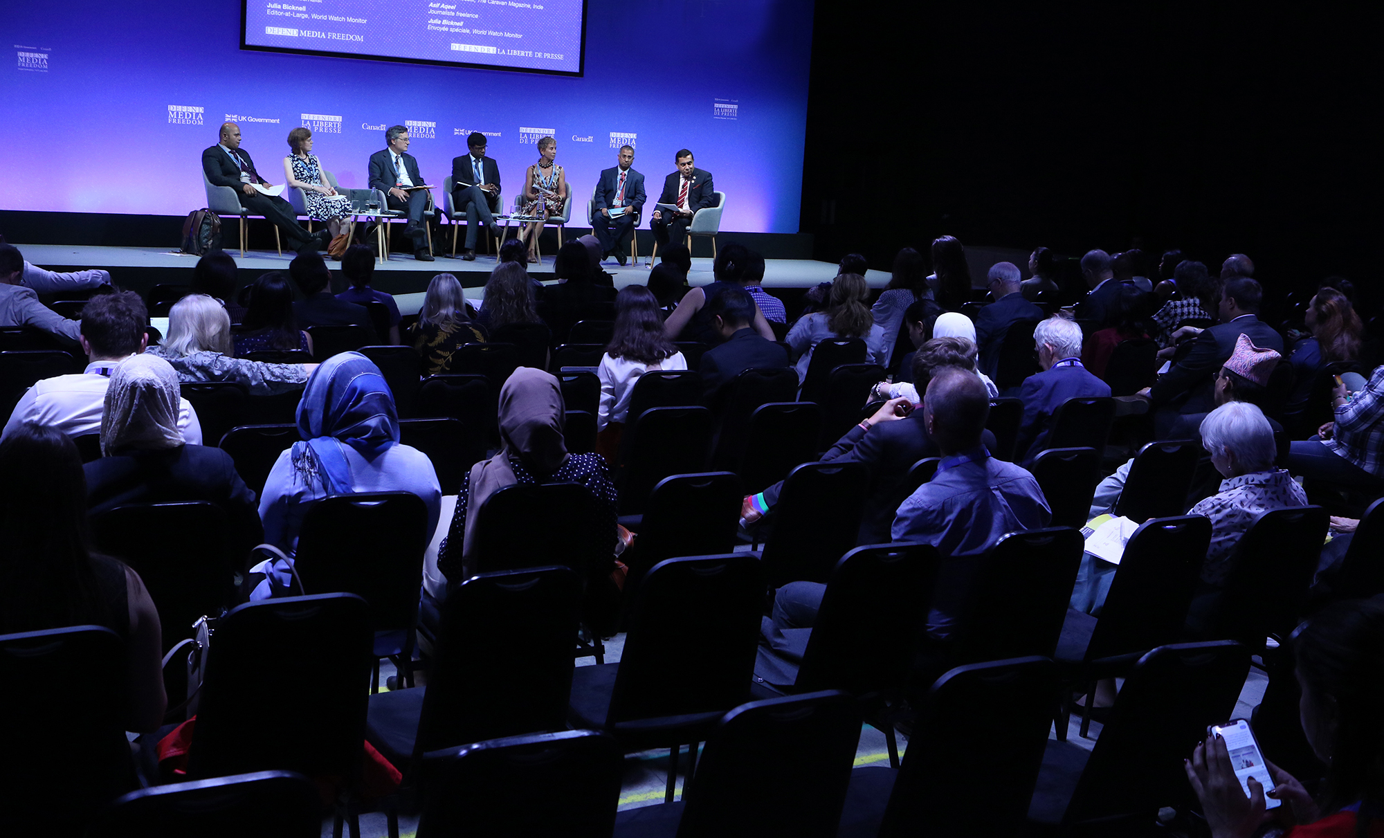 People sitting at a conference and listening to a panel.