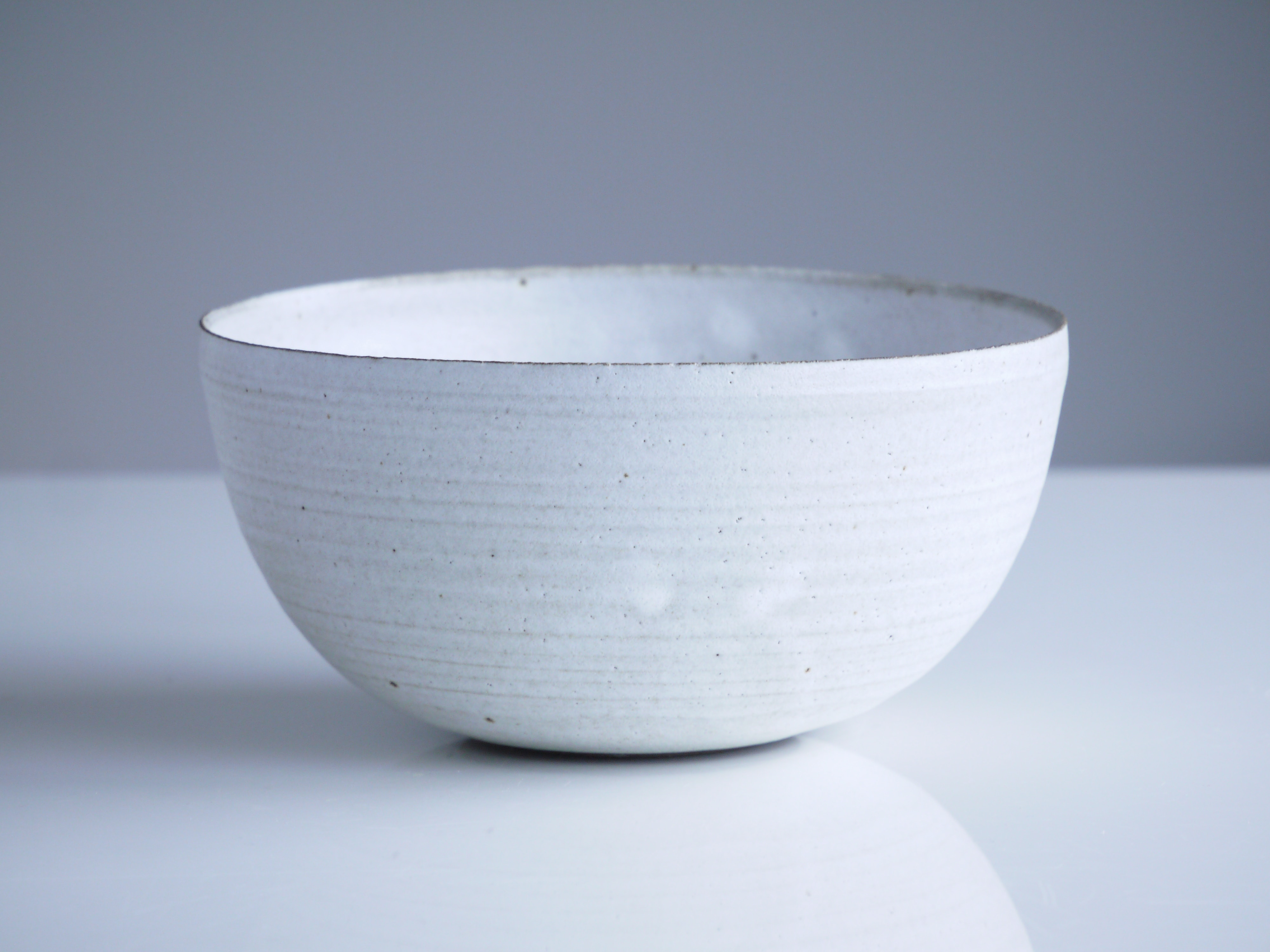 Closeup of a white bowl on a white table.
