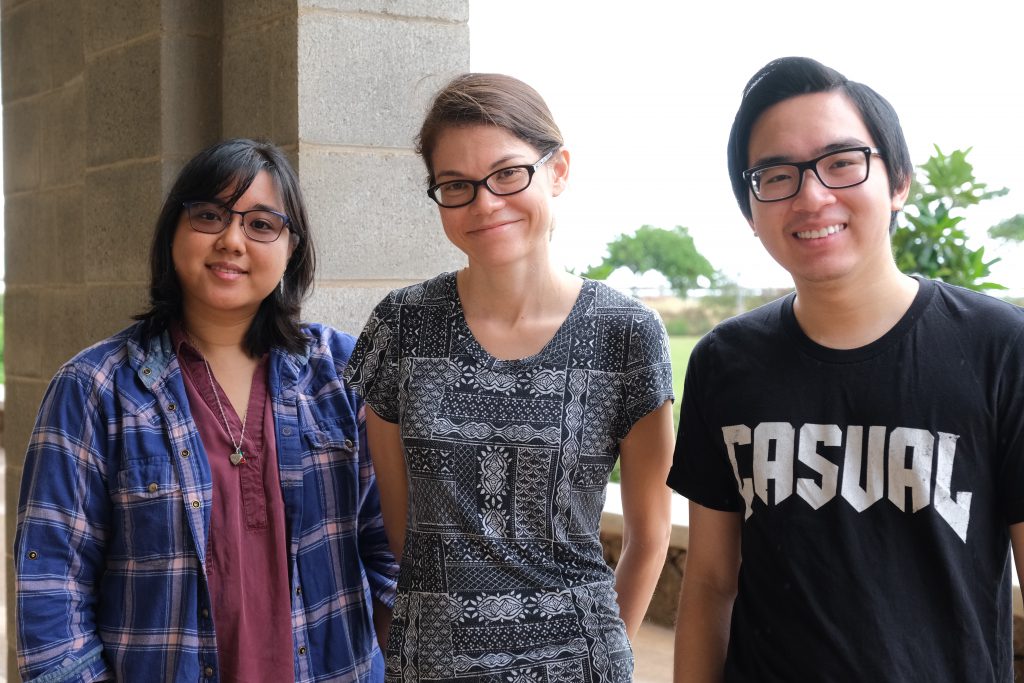 Outdoor group photo of a professor standing between two of her students. 