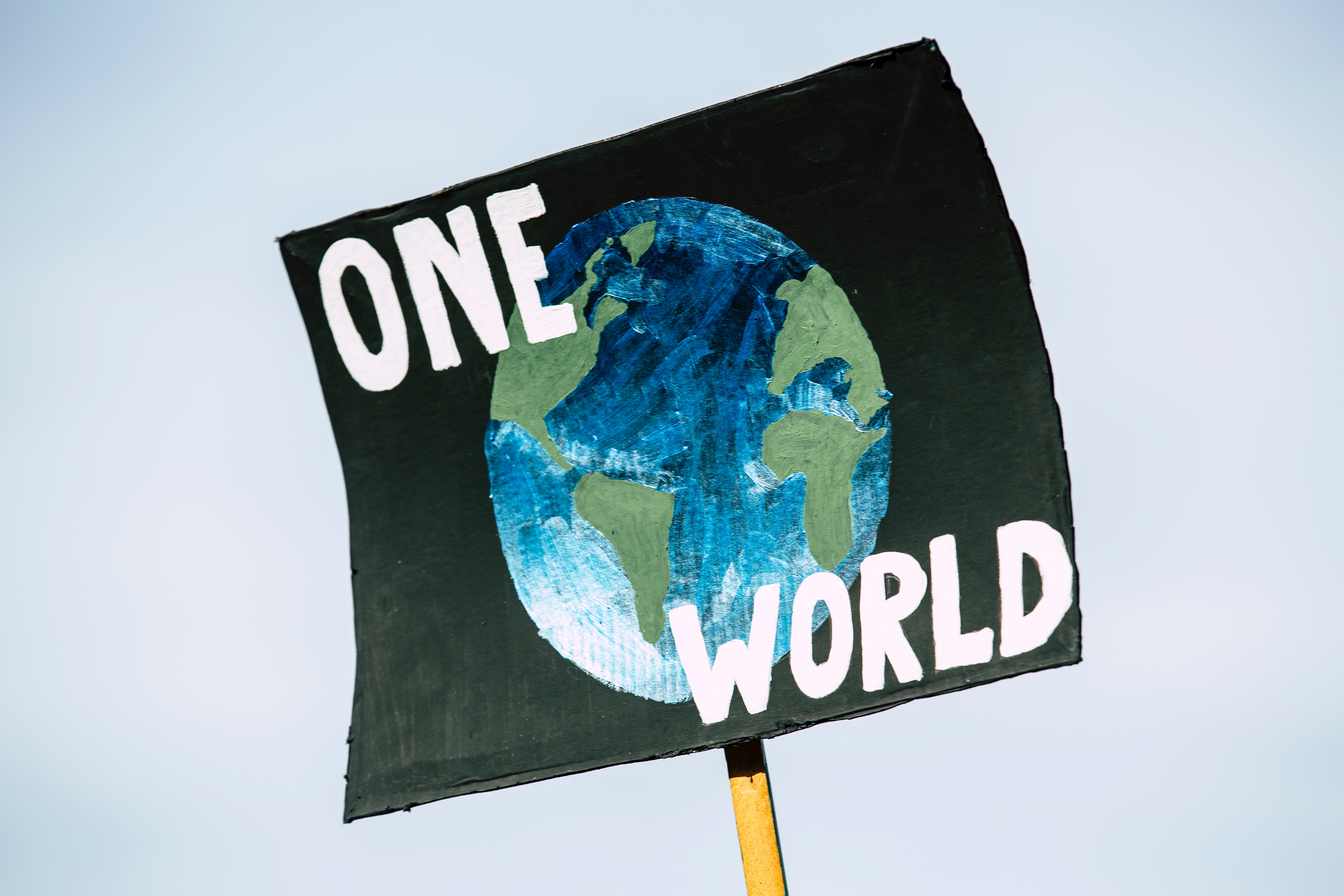 Sign that says "One World" with a picture of Earth.