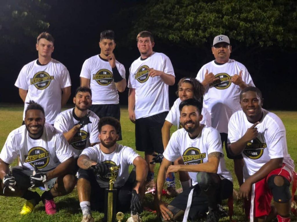 Group photo of flag football players, kneeling and standing on a field.