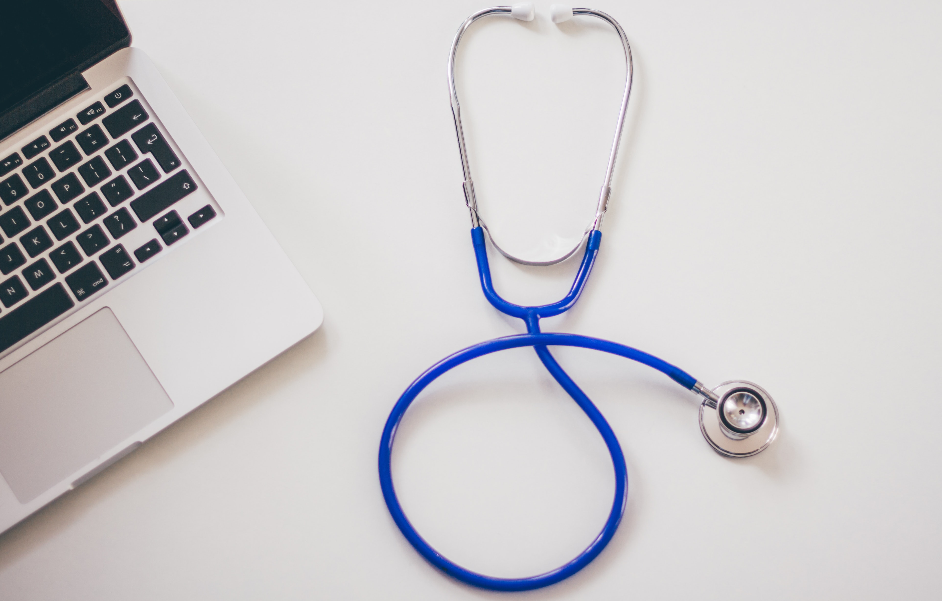 A stethoscope and laptop on a table.