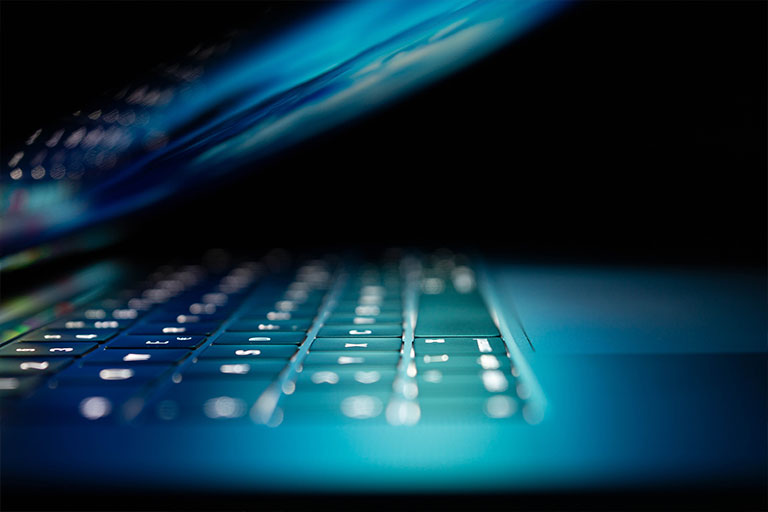 A lit-up laptop in a dark setting.