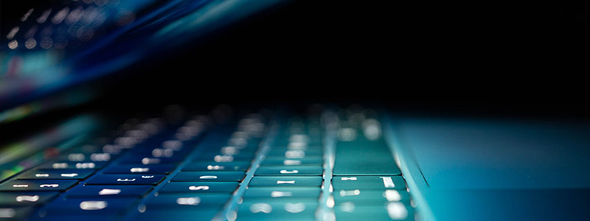 A lit-up laptop in a dark setting.