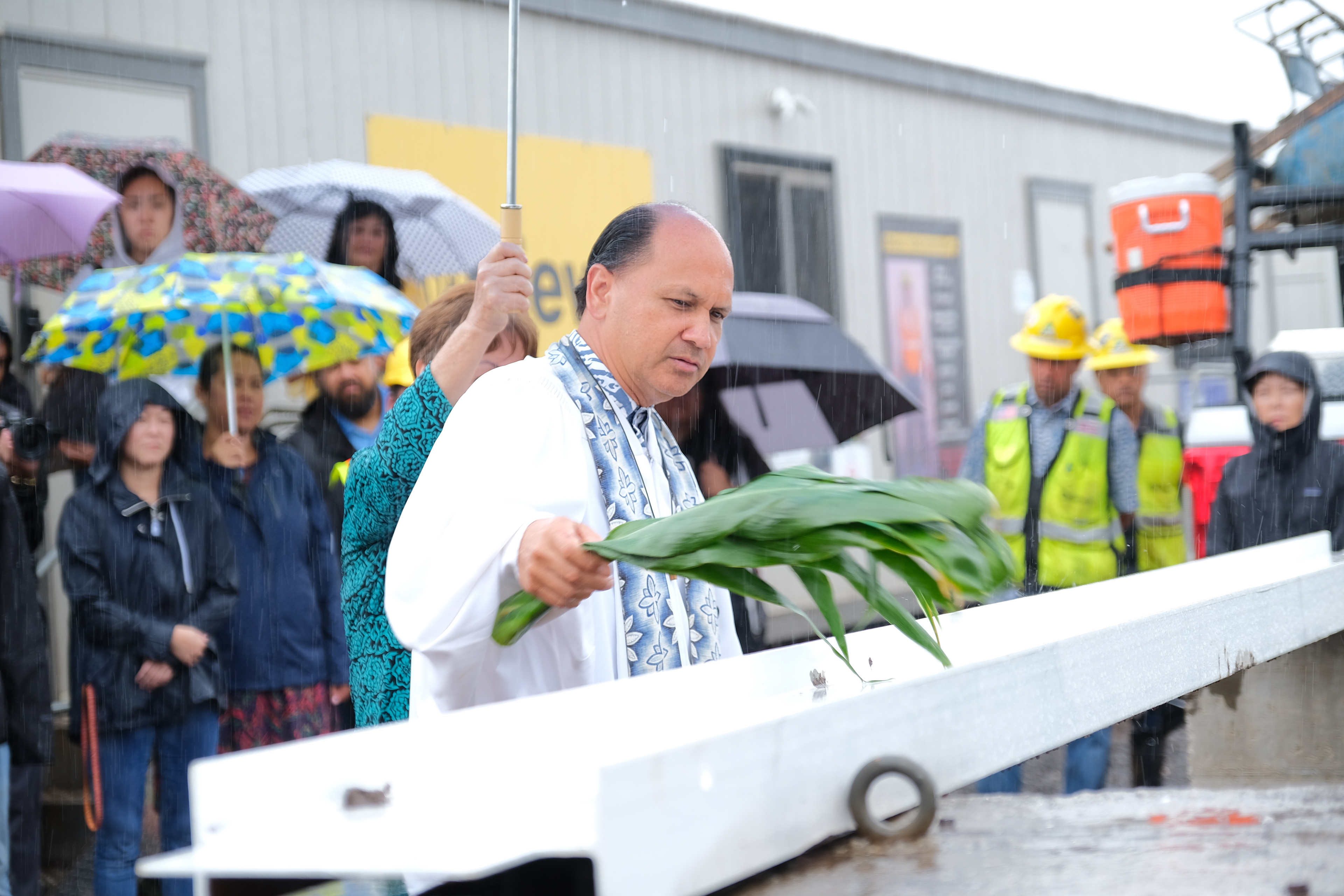 Kahu Kordell Kekoa blesses the beam by sprinkling water with a ti leaf.