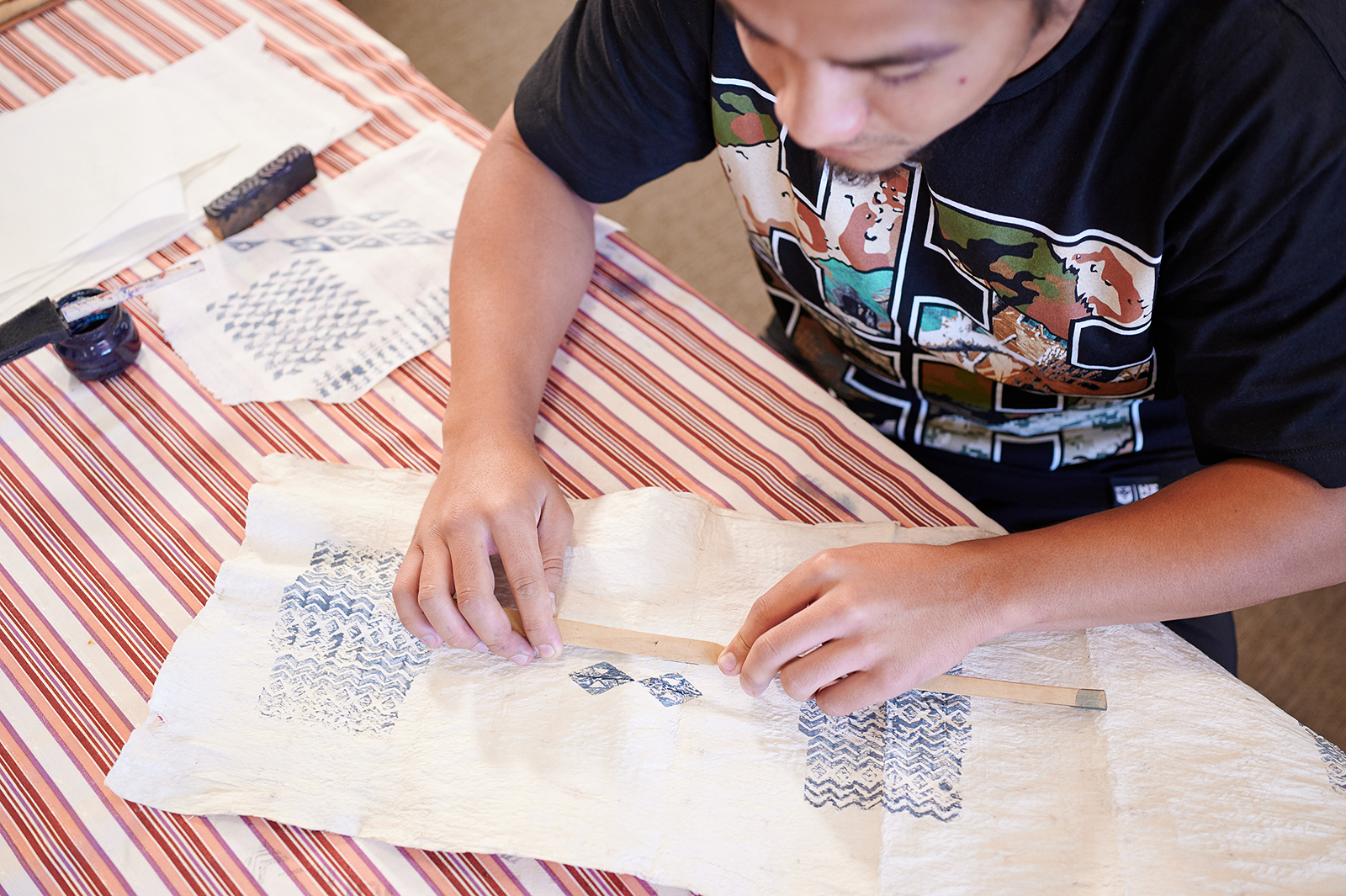 Person stamping geometric patterns on a cloth.