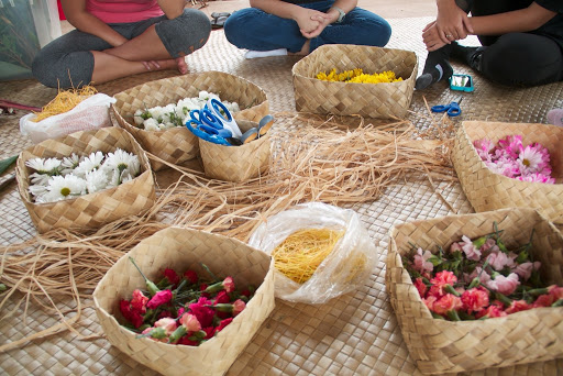 Various plant materials sorted in woven baskets, all on a woven mat on the floor.