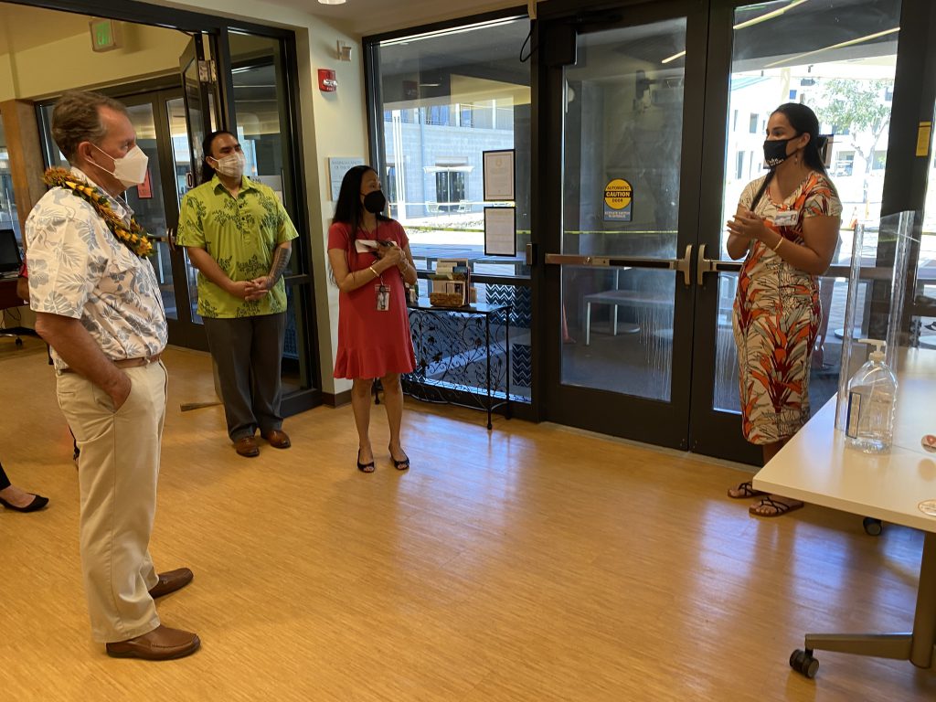 A group stands around in a discussion at the Naʻulu Center.