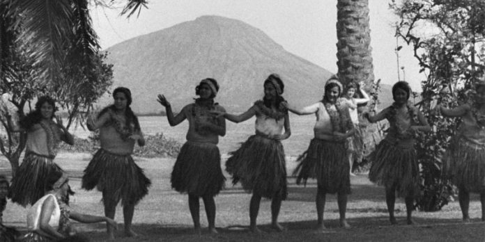 Black and white image of hula dancers with Diamond Head in the background.