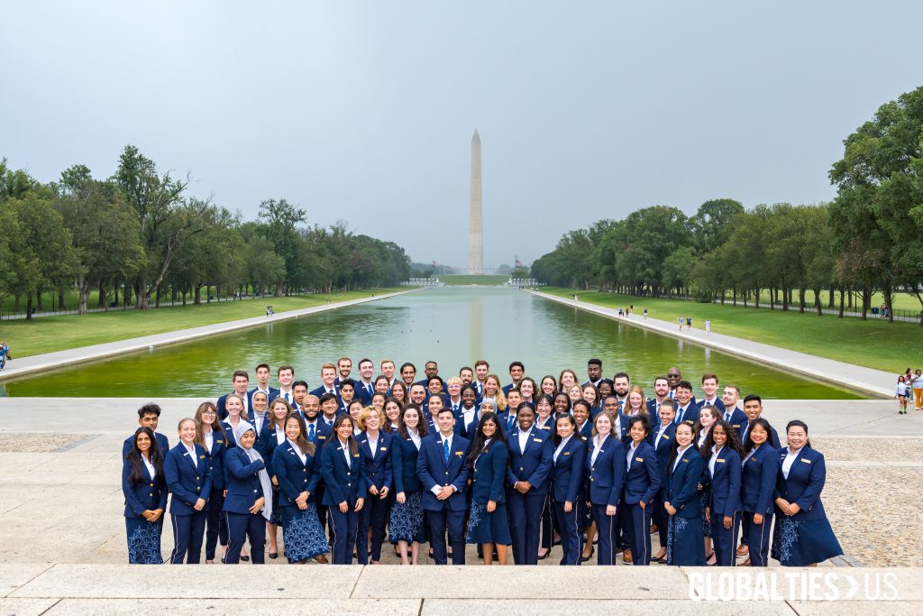 Dozens of men and women pose for a group photo with the Washington Monument in the background.
