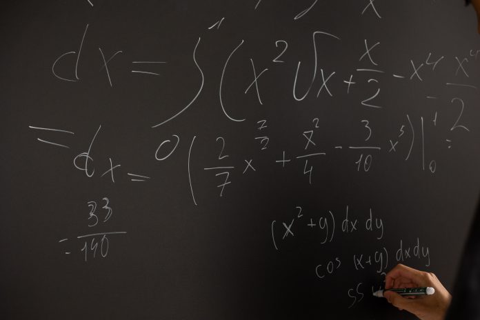 Math equation written in chalk on a blackboard.