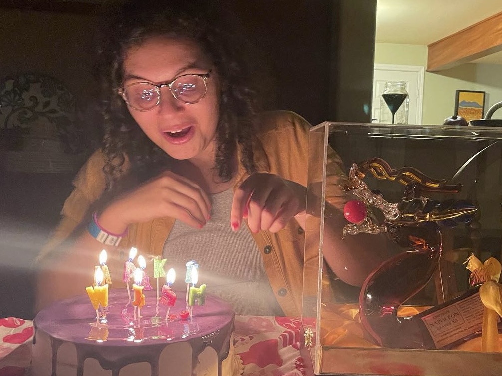 Woman looking at a birthday cake with lit candles.
