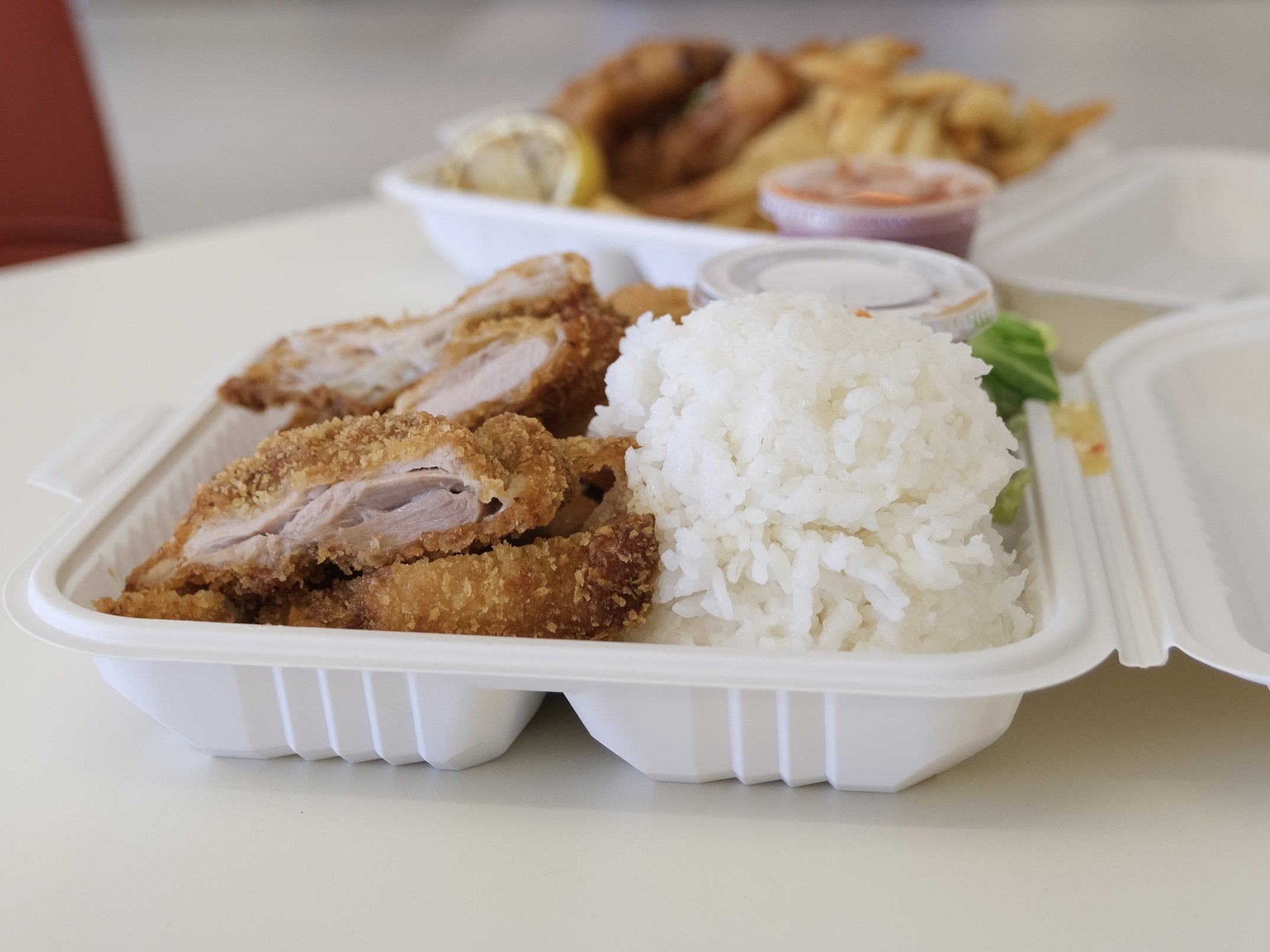 A plate of chicken katsu (foreground) and a plate of fish and chips.