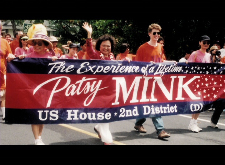 Screengrab of a video with people holding a banner that says, "Patsy Mink."