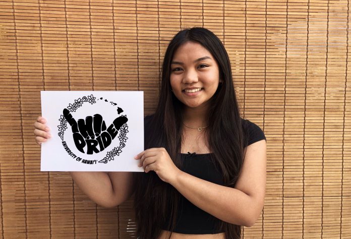 A woman holding a white paper with a black design on it. The design features an illustration of a shaka and the words HI Pride.