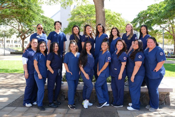 Pre-nursing students posing for a group photo and wearing blue scrubs.