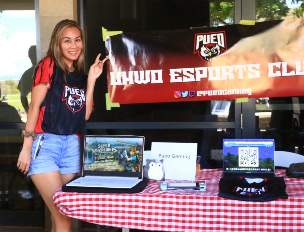 Incoming student posing next to the Pueo Gaming Club booth.