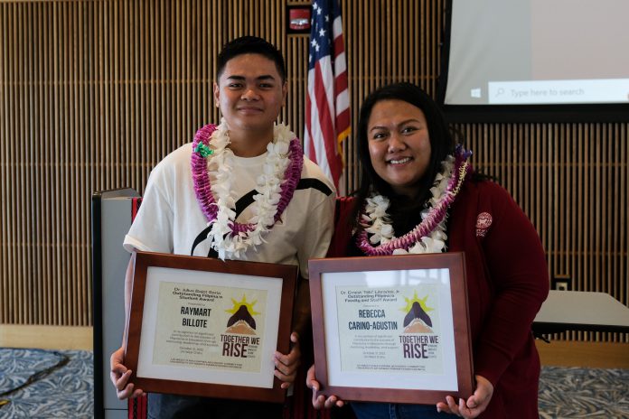 Two people wearing lei and holding certificates.