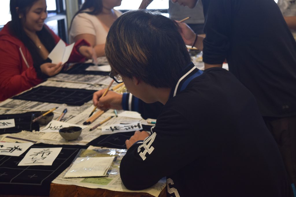 Students at a table doing calligraphy.