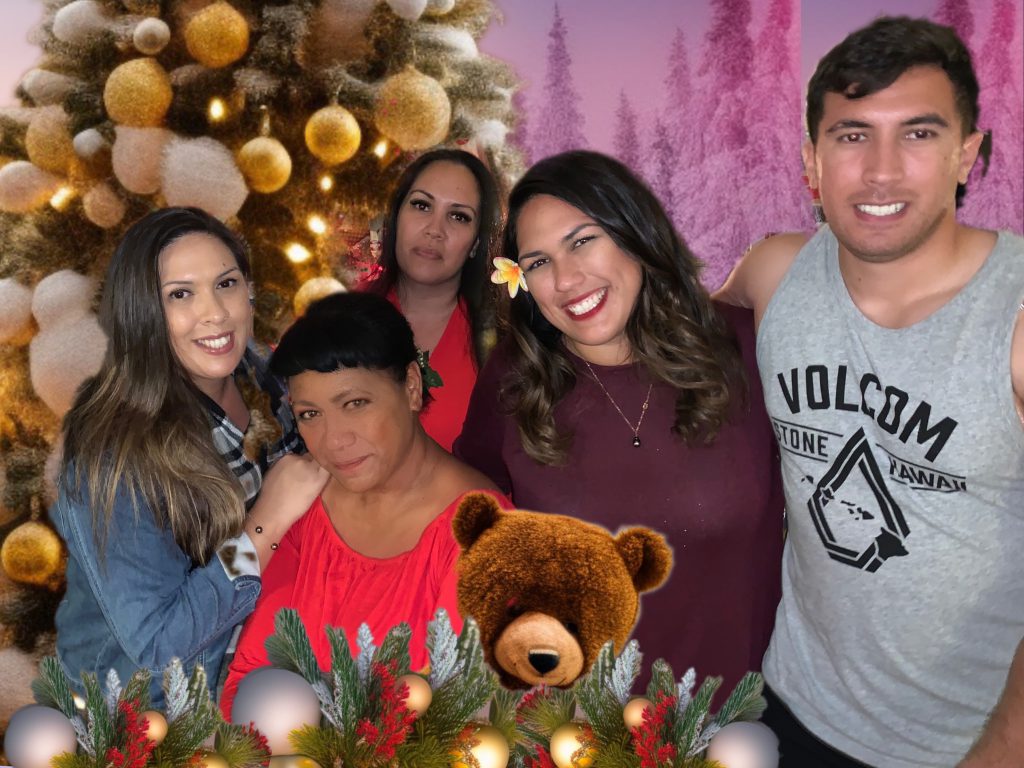 A group of five people with a Christmas tree in the background.