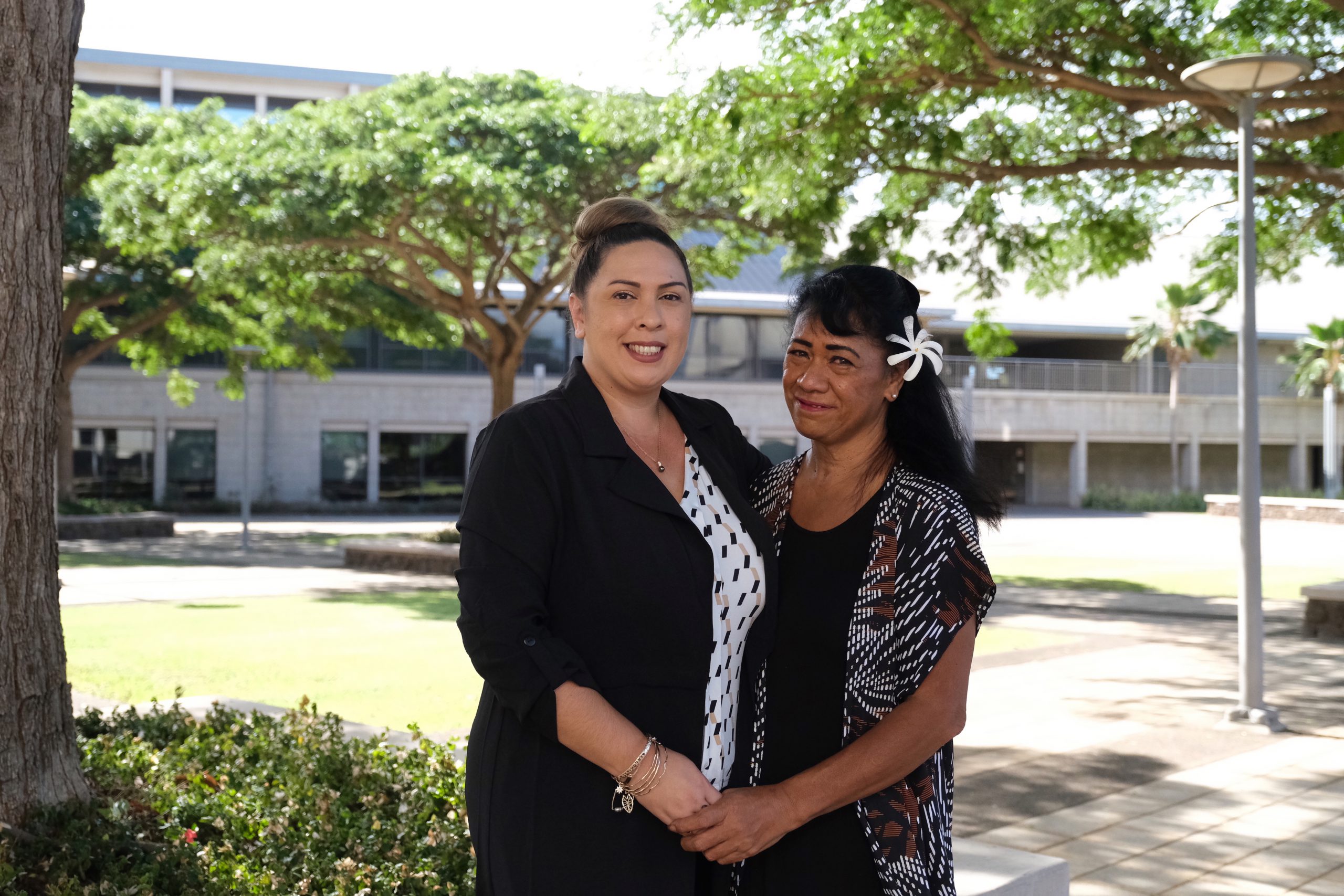 Two women standing outdoors in a courtyard and holding hands.