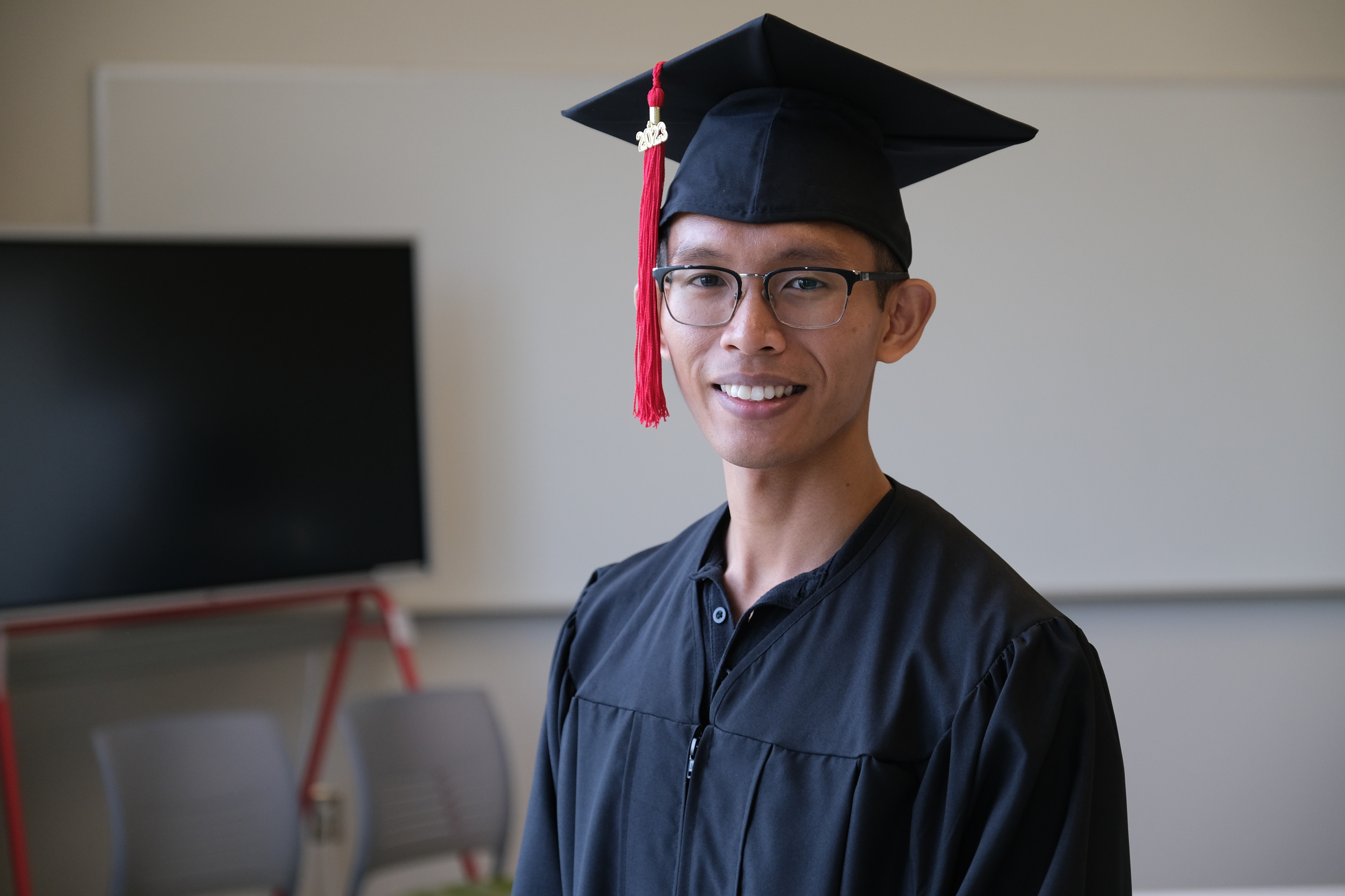 Portrait of Anthony Miguel wearing his commencement cap and gown.