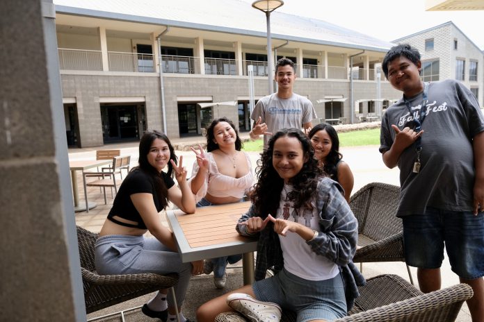 A group of students sitting at an outdoor courtyard.