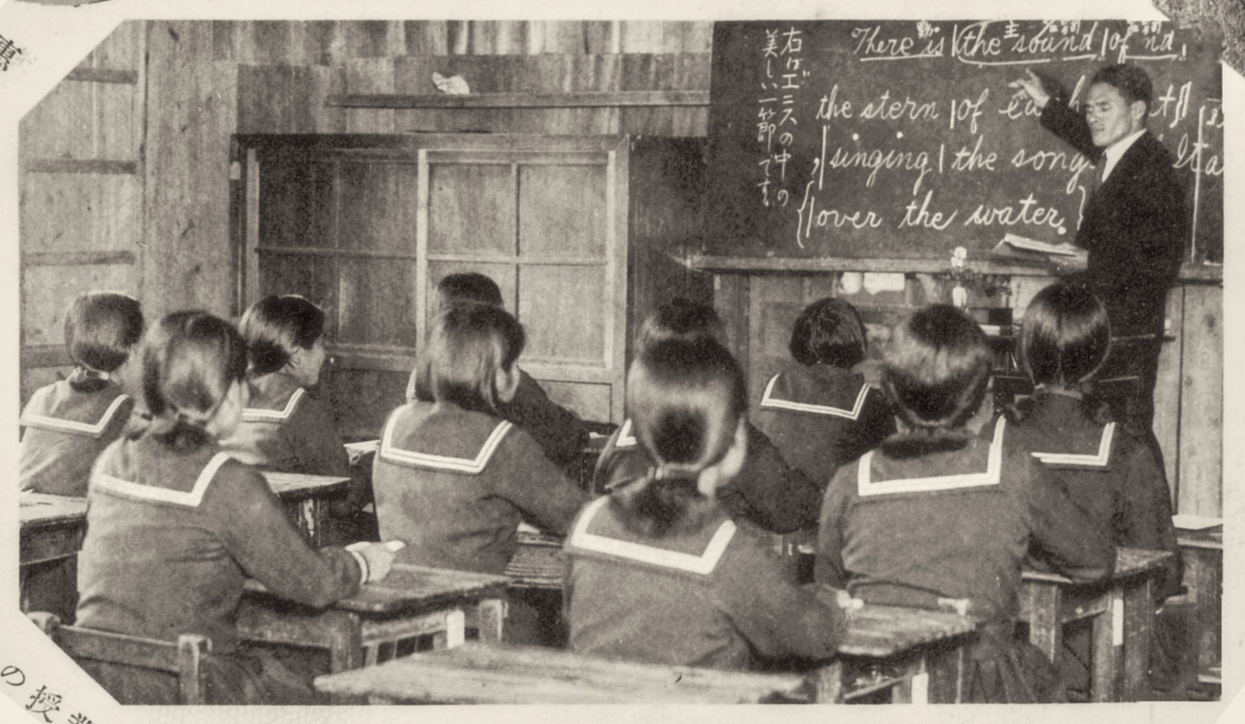Black-and-white image of students and a teacher in a classroom from the "Himeyuri and Hawaii" exhibit.