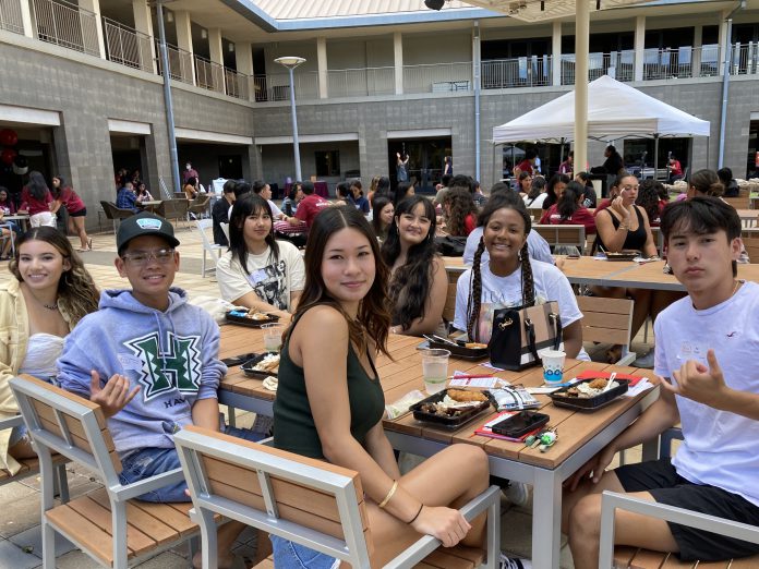 A group of students sitting at a table at an outdoor courtyard.
