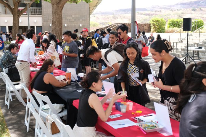 Dozens of students visit activity and information tables at an outdoor courtyard at U H West Oahu.