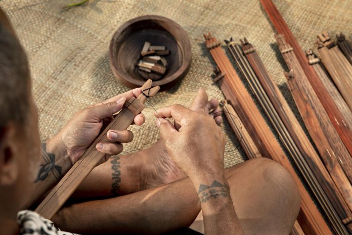 Closeup of hands crafting a stringed instrument.