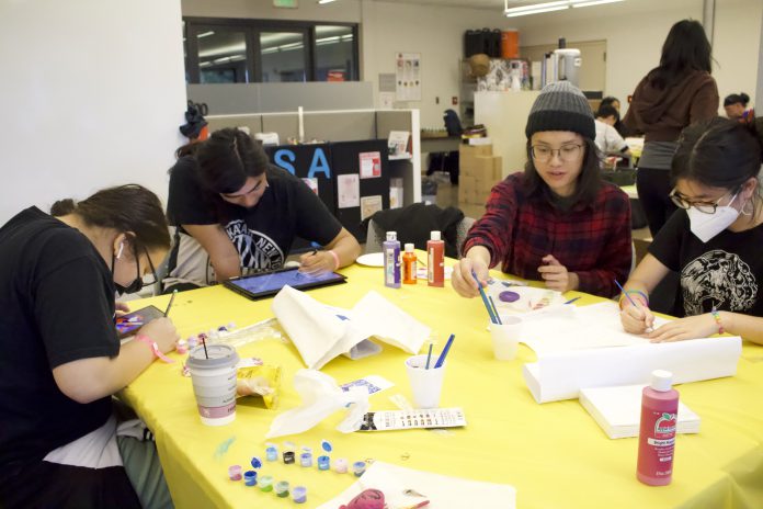 Students sitting at a table and doing art activities.