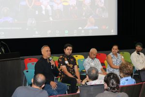 Four speakers seated in front of an audience.