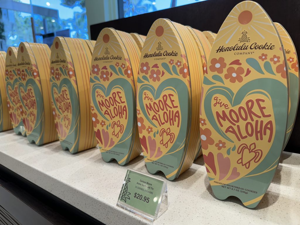 A row of surfboard-shaped cookie tins on a store shelf.